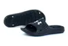 A pair of black Under Armour slides shown against a white background. One slide is shown from the side, and the other is shown from the underneath view. Produktbild-Vorschau