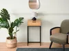 A narrow console table with a drawer and a lamp on top, placed next to a green armchair and a large potted plant. Produktbild-Vorschau
