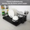 A black dish rack on a countertop with dishes, glasses, and cutlery. Produktbild-Vorschau
