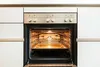 An open oven with racks inside, illuminated by the oven light. Produktbild-Vorschau