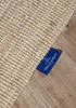 A close-up of a woven rug with a blue tag attached. Podgląd zdjęcia produktu