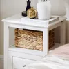 A white bedside table with a woven basket and books on top. Náhľad obrázku produktu