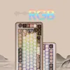 Two mechanical keyboards are displayed against a light beige background with abstract mountain scenery at the bottom. The word "RGB" with a rainbow gradient is overlaid at the top. Produktbild-Vorschau