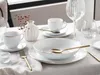 A table setting with white porcelain dishes and gold accents. Produktbild-Vorschau