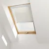 A close-up view of a white blackout roller blind installed in a wooden-framed attic window. Produktbild-Vorschau