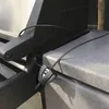 A close-up shot of a black cable lock securing a gray lid to a black grill. Podgląd zdjęcia produktu
