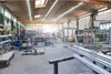 A wide shot of a workshop or factory floor, filled with various metal structures, equipment, and materials. The scene suggests an industrial or manufacturing environment. Voir les images du produit