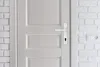 A close-up view of a white door with a white door handle and lock. Produktbild-Vorschau