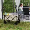 A garden wagon filled with produce sits on grass in front of a patio where two people are seated at a table. Produktbild-Vorschau