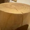 A close-up view of a wooden stool with visible wood grain and cracks. Produktbild-Vorschau
