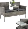 A grey rattan garden bench with a built-in table, a plant, and a cup on it, shown against a white background. Náhled obrázku produktu