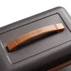 A close-up shot of a brown handle on a textured gray suitcase. Produktbild-Vorschau