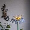 A decorative metal flower with LED lights and a metal gecko decoration on a wall. Produktbild-Vorschau