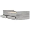 A grey wooden bed frame with two drawers pulled out, shown from a side angle against a white background. Produktbild-Vorschau