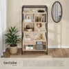 A bookshelf filled with decorative items and books, next to a potted plant, with an oval mirror on the wall. Produktbild-Vorschau