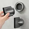 A hand is holding a hair dryer attachment, with two other attachments mounted on a wall. Produktbild-Vorschau
