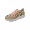 A single beige sneaker with a colorful woven pattern and pink laces is shown against a white background. Voir les images du produit
