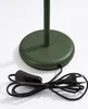 Close-up of the base of a green table lamp, showing the power cord and plug. Voir les images du produit