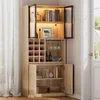 A tall, light wood cabinet with glass doors and interior lighting, displaying books, wine bottles, glasses, and decorative items. Náhled obrázku produktu