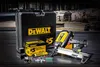 A DeWalt cordless gas nailer kit with its case and accessories, displayed on a dark, textured surface with a blurred construction site in the background. Produktbild-Vorschau