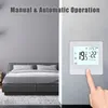 A digital thermostat is shown mounted on a wall next to a bed in a bedroom. The thermostat displays temperature and time. Náhled obrázku produktu