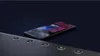 A smartphone is placed on a dark, textured surface next to a soundbar with illuminated buttons. Produktbild-Vorschau