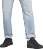 A close-up view of a person's legs wearing light blue jeans and black Puma sneakers. Podgląd zdjęcia produktu