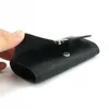 A hand holding a black leather coin purse with a snap closure. Produktbild-Vorschau