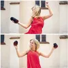 A woman in a red dress is dancing and holding two black Bluetooth speakers. Náhled obrázku produktu