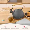 A kettle and a cup of tea on a wooden countertop, with pastries in the background. Náhľad obrázku produktu