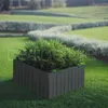A dark gray planter box filled with green foliage sits on a lush green lawn, with a winding hedge and more lawn in the background. Náhled obrázku produktu