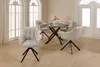 A dining set with a round table and four chairs in a room with large windows. Produktbild-Vorschau