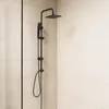 A black shower system mounted on a tiled wall. Produktbild-Vorschau
