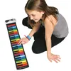 A young girl is playing a rainbow-colored roll-up piano keyboard. Produktbild-Vorschau