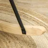 A close-up view of the base of a rocking chair, showing the wooden rocker and a black metal support leg attached with a screw. The chair rests on a textured rug. Anteprima dell’immagine prodotto