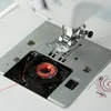 A close-up view of the needle and bobbin area of a sewing machine. Produktbild-Vorschau