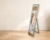 A full-length mirror with shelves and hanging space for clothes, set against a neutral wall and wooden floor. Náhled obrázku produktu