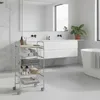 A bathroom with a rolling cart filled with towels and toiletries, a vanity with a mirror, and a bathtub. Voir les images du produit