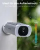 A white security camera with a solar panel is mounted on a white wall, with water droplets on it, indicating outdoor use. A temperature gradient scale is shown on the right. Produktbild-Vorschau