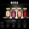 Four bottles of BOSS The Scent perfume are displayed on a dark, reflective surface, with descriptive text below. Anteprima dell’immagine prodotto