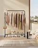 A clothing rack with clothes and shoes displayed in a room. Náhled obrázku produktu