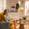 A woman relaxing in a chair while listening to music from a projector. Produktbild-Vorschau