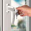 A hand is inserting a key into a lock on a window handle. Produktbild-Vorschau