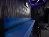 A modern, dimly lit room with a long blue sofa and textured walls, illuminated by purple lighting. Produktbild-Vorschau