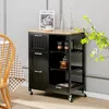 A black kitchen cart with a wooden top is shown in a room with a checkered tablecloth and chair. Podgląd zdjęcia produktu