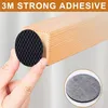 A hand is shown applying a black, textured, circular anti-slip pad to the corner of a wooden furniture leg. A smaller inset image shows a gray felt pad. Produktbild-Vorschau