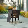 A black metal fire pit with a lid is shown on a patio with flames inside. Náhled obrázku produktu