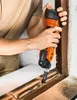 A person is using an oscillating multi-tool to remove material from a wooden window frame. Náhľad obrázku produktu