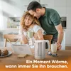 A couple is in a kitchen, the man is embracing the woman from behind while she holds a mug and laughs. There is a tablet, pastries, and a kettle on the table. Anteprima dell’immagine prodotto