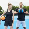 A man and a woman are standing outdoors on a blue surface, holding medicine balls. Náhľad obrázku produktu